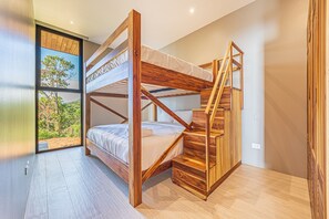 A bunk bed with a wooden frame, a staircase, and a large window with a view of trees. - Professional CHEF Included! Oceanview 6 Bedrooms Villa, Pool, Heated Hot Tub (Puntarenas Province)