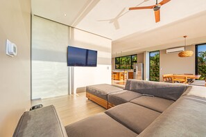 A modern living room with a large sectional sofa, a flat-screen TV, and a ceiling fan. - Professional CHEF Included! Oceanview 6 Bedrooms Villa, Pool, Heated Hot Tub (Puntarenas Province)