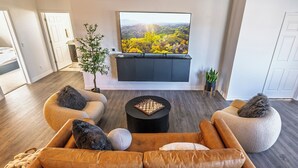 A modern living room with a leather sofa, a coffee table, and a flat-screen TV mounted on the wall. -  New Modern Downtown Penthouse Condo with undercover parking (Flagstaff)
