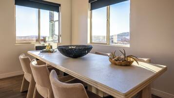 A dining area with a long table, beige chairs, a black woven bowl, and a small plant.