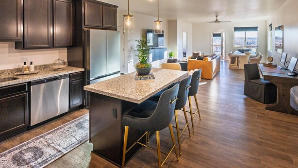 A modern kitchen with granite countertops, stainless steel appliances, and a central island with bar stools. -  New Modern Downtown Penthouse Condo with undercover parking (Flagstaff)