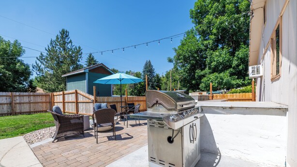 A backyard with a barbecue grill, outdoor furniture, and a wooden deck. - 8th St Retreat: Loveland Comfort (Loveland)