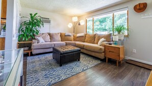 A cozy living room with a sectional sofa, a glass coffee table, and a patterned rug. - 8th St Retreat: Loveland Comfort (Loveland)