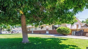 A residential area with a large tree, a well-maintained lawn, and houses with visible windows and doors. - 8th St Retreat: Loveland Comfort (Loveland)