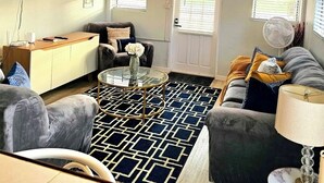 A living room with a sofa, armchair, coffee table, and a TV mounted on the wall. - Entire rental unit in Calibishie, Dominica (Calibishie)