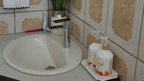 A bathroom with a sink, mirror, towel rack, and a potted plant. - Entire rental unit in Calibishie, Dominica (Calibishie)