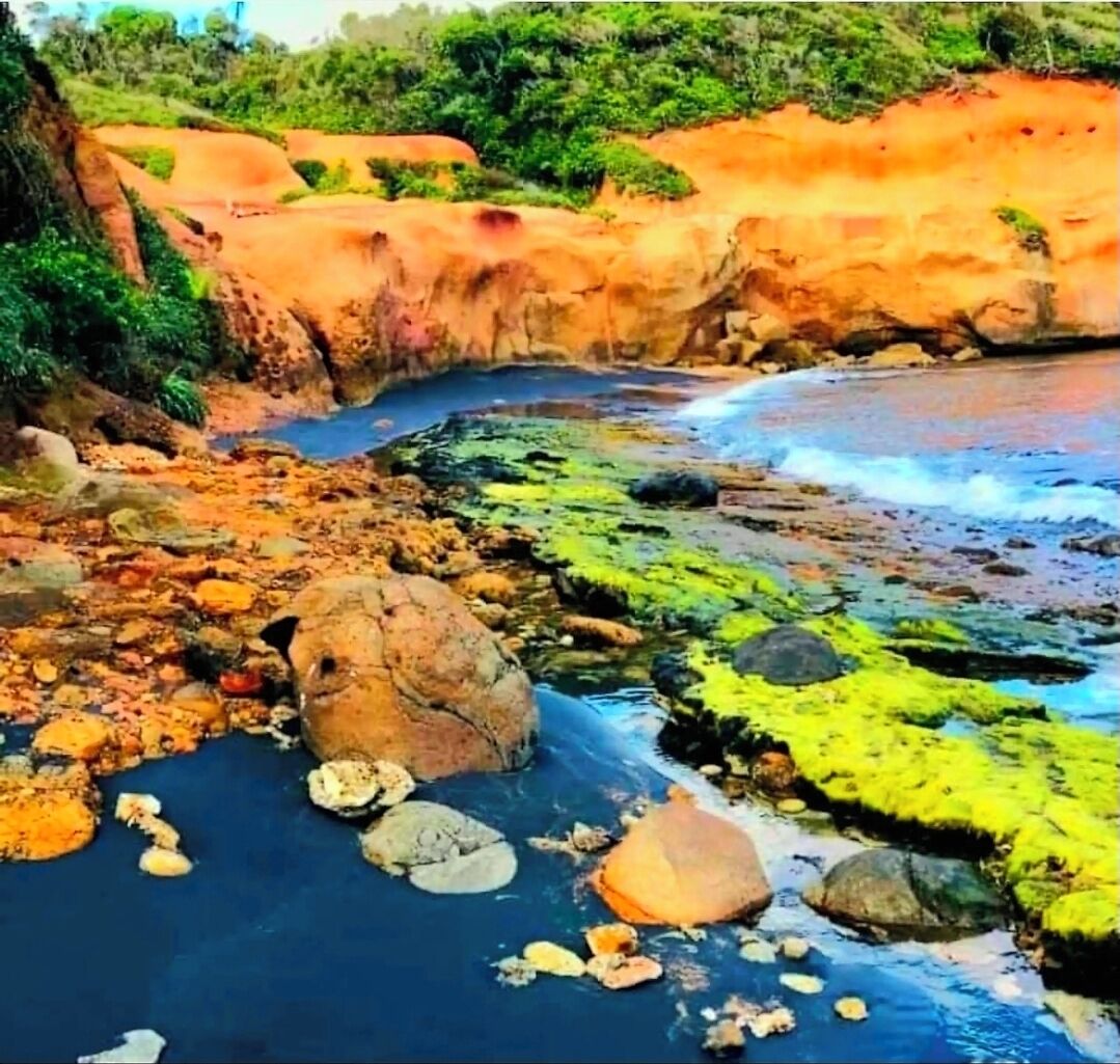 Paisaje costero con terreno rocoso y una masa de agua azul cristalina.