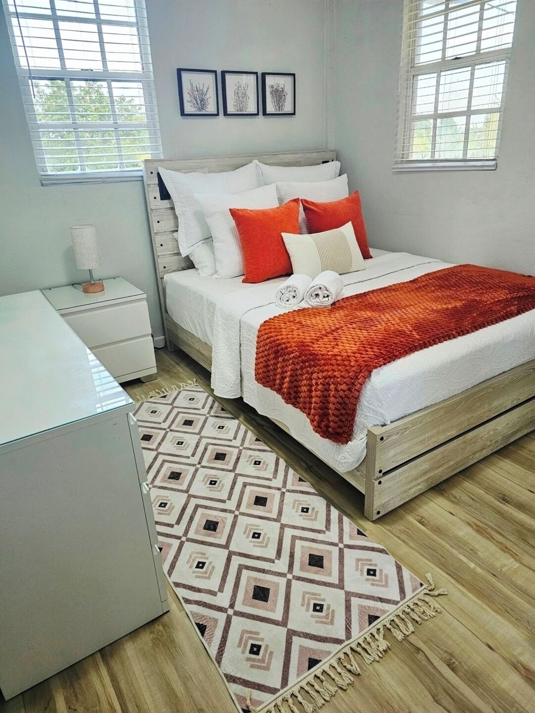 Un dormitorio con cama, mesita de noche y una alfombra estampada.