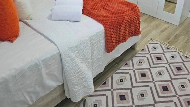 A bedroom with a bed, white curtains, a window, an air conditioning unit, and a wardrobe. - Entire rental unit in Calibishie, Dominica (Calibishie)