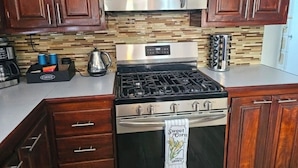 A kitchen with wooden cabinets, a stainless steel stove, a microwave, and a coffee maker. - Entire rental unit in Calibishie, Dominica (Calibishie)
