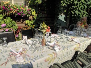 An outdoor dining area with a table set for a meal, surrounded by lush greenery and flowers. - Laughing Horse Lodge (Bigfork)