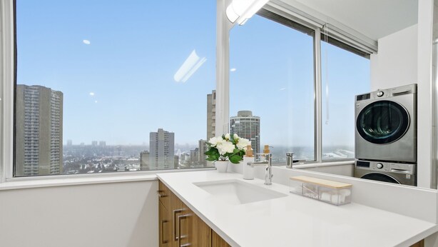 Eine moderne Küche mit großem Fenster, einer eingebauten Waschmaschine und einem Holzkasten.