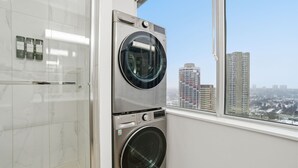 Ein Waschraum mit gestapelten Waschmaschinen und Blick auf hohe Gebäude durch ein Fenster.