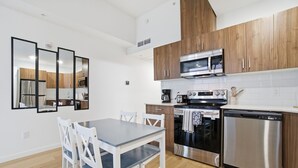 Eine moderne Küche mit Holzschränken, Edelstahlgeräten und einem Essbereich mit Tisch und Stühlen.
