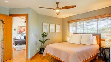 A bedroom with a bed, ceiling fan, and a potted plant.