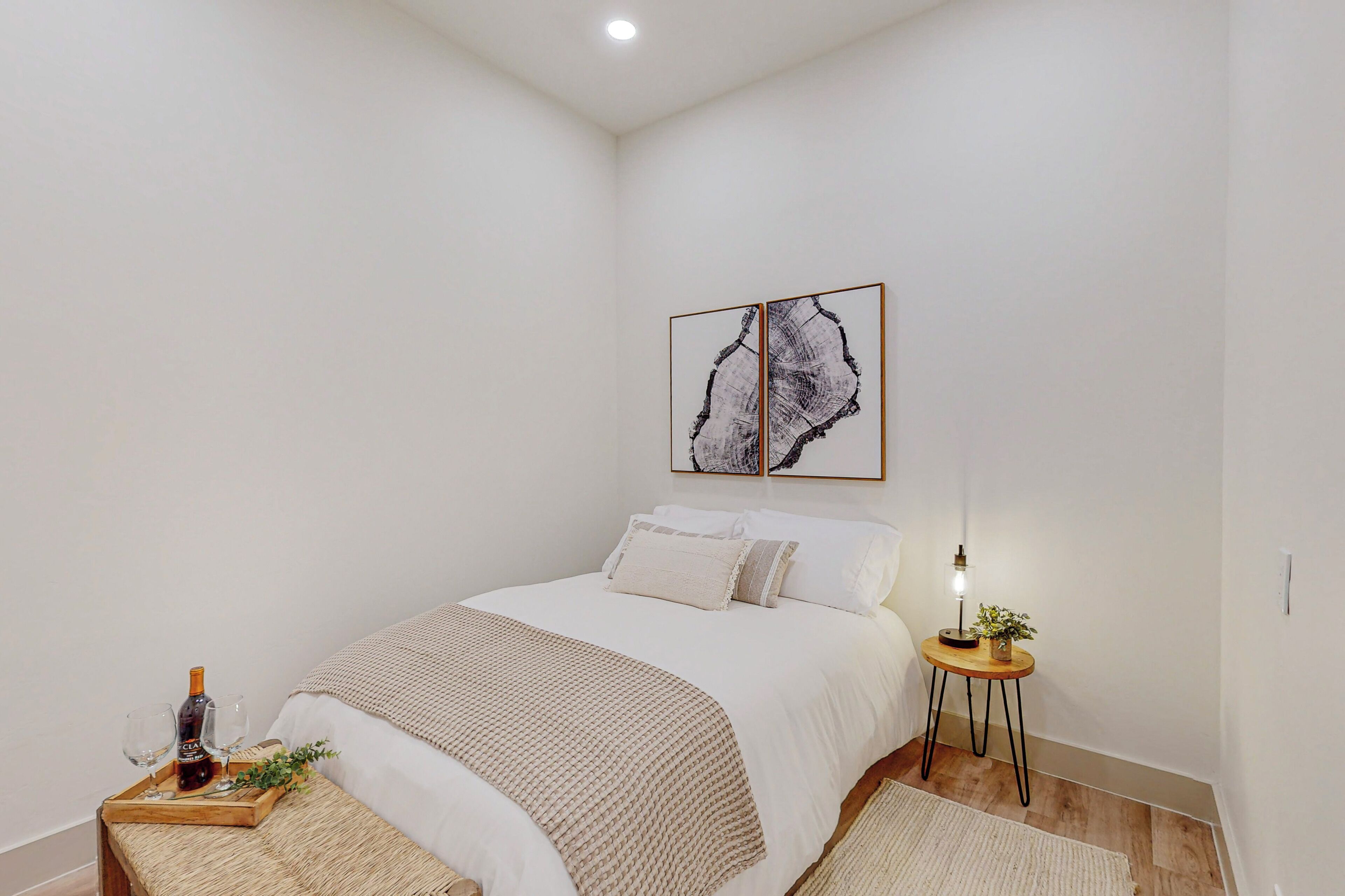 A bedroom with a bed, bedside table, and a wall-mounted artwork.