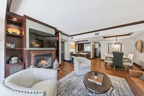 A modern living room with a fireplace, a dining area, and a kitchen.