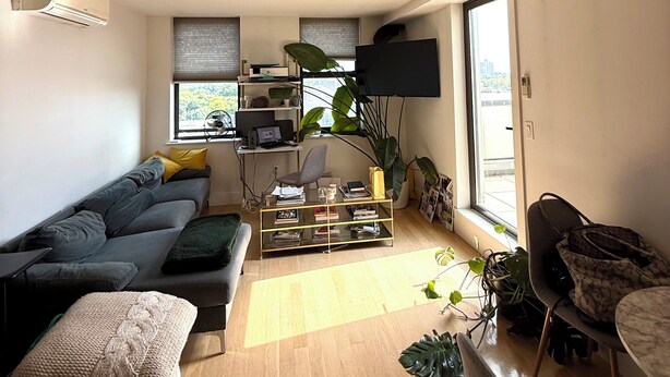 Ein modernes Wohnzimmer mit einer Couch, einem Couchtisch und einem an der Wand befestigten Fernseher.