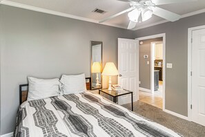 Une chambre à coucher comprenant un lit, des lampes de chevet, une table de nuit et une porte donnant sur une salle de bain.