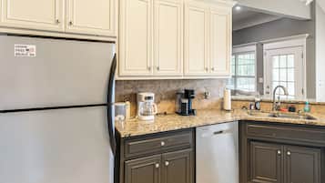 A kitchen with a refrigerator, coffee maker, and a sink.