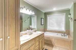 Une salle de bain avec deux lavabos, un grand miroir et une baignoire.