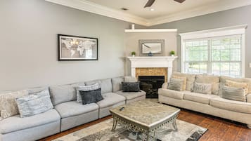A living room with two sofas, a fireplace, a ceiling fan, and a world map artwork.