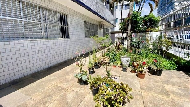 A courtyard with potted plants and a tiled floor. - Cozy and very well-located apartment in a condominium. (Praia Grande)
