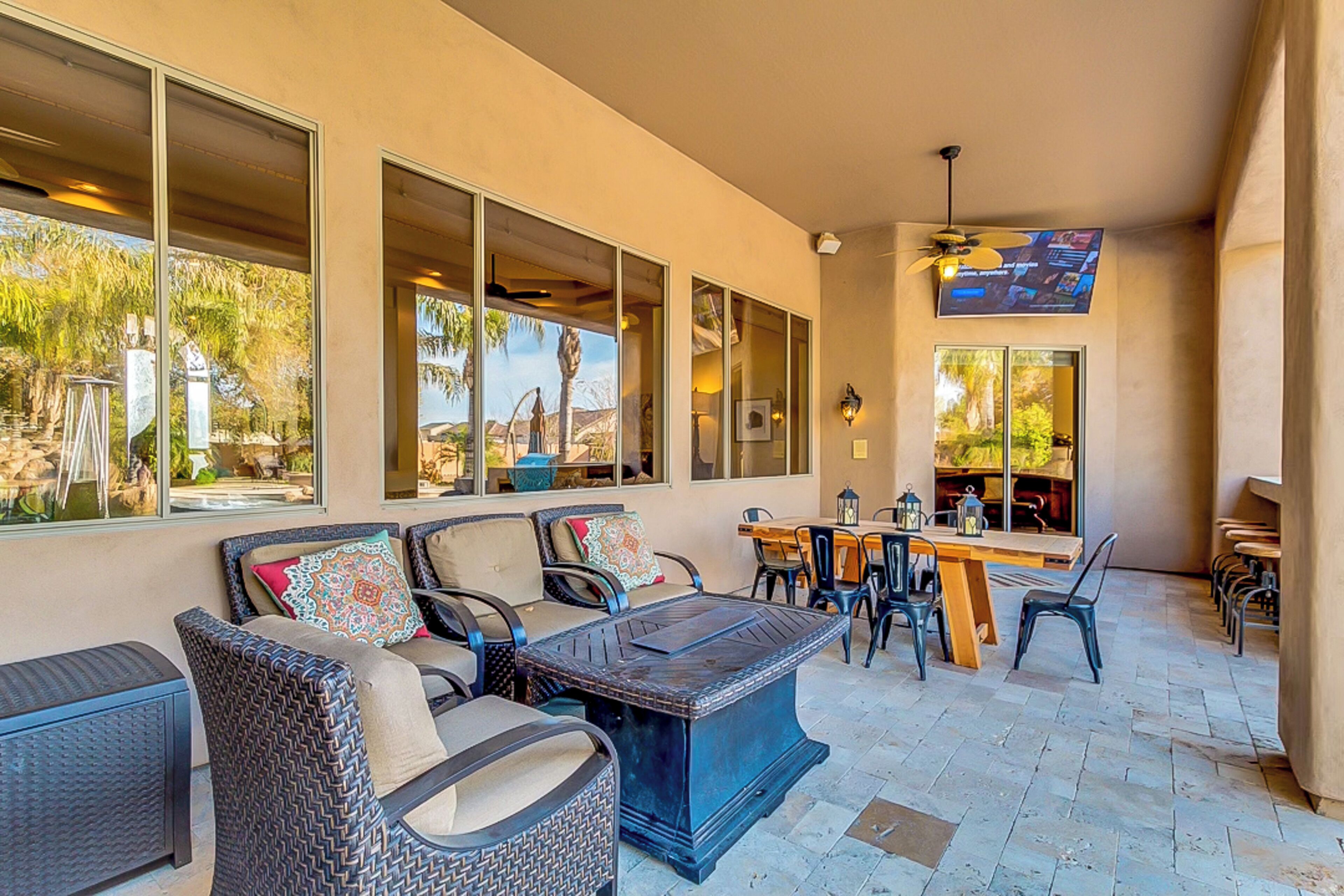 Un patio soleado con mobiliario exterior, ventanas amplias y un ventilador de techo.