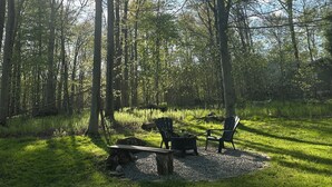 A forested area with a picnic table and chairs, surrounded by trees and a clear sky.