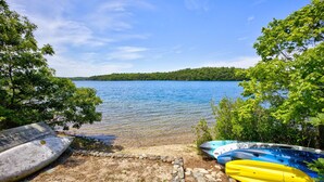 A lakeside view with kayaks and a wooden dock. - 5 Bedrooms | Water Views | Private Pond Beach (Brewster)