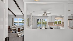 A modern interior with a kitchen, dining area, and a balcony with a view. - 5 Bedrooms | Water Views | Private Pond Beach (Brewster)