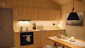 Une cuisine moderne avec des meubles en bois, un four encastré, un évier et un coin repas comprenant une table et un banc.