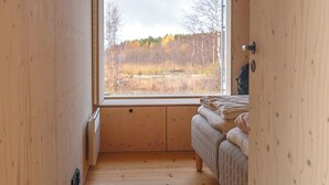 Une pièce de cabane en bois comprenant un lit, une fenêtre et un luminaire au plafond.
