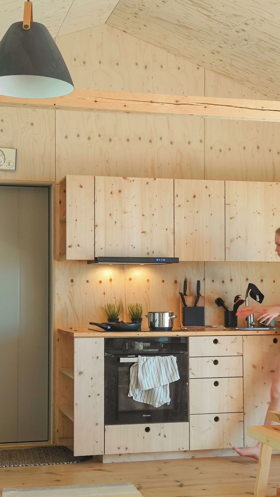 Et køkken med træskabe, en komfur og en hængende lampe.