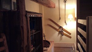 Ein Holzraum mit schrägem Dach, einer Holzleiter und einem an der Wand befestigten Skiständer.