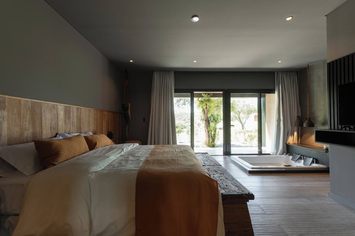Un dormitorio moderno con una cama grande, una bañera y vistas al exterior.