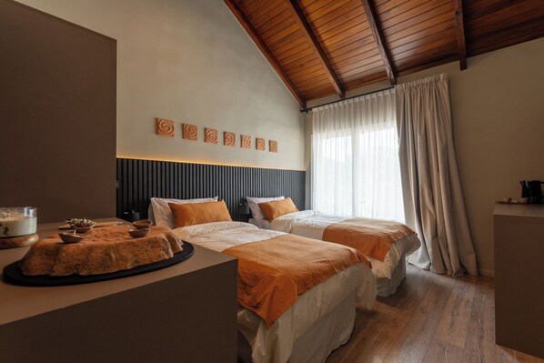 A hotel room with two beds, a wooden ceiling, a window with curtains, and a bedside table with a lamp. - Wayna Lodge de sierras (Salsipuedes)