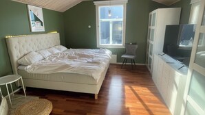 Ein Schlafzimmer mit Bett, Fenster, Fernseher und Kleiderschrank.