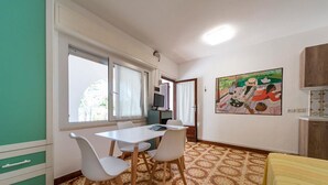 A room with a dining table, chairs, a TV, and a painting on the wall. - Pal Friul - Villa Marinella (Mola)