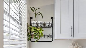 A room with white cabinets, a black metal plant hanger with the word "GROW" on it, and a potted plant. - Charming 1-bedroom chalet in Melbourne awaits you. (Melbourne)