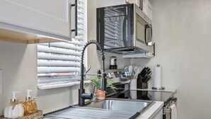 A modern kitchen with a stainless steel sink, a coffee machine, and a microwave. - Charming 1-bedroom chalet in Melbourne awaits you. (Melbourne)