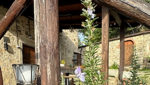 Un espace extérieur aménagé dans un style rustique, avec un mur en pierre, des poutres en bois et une chaise en métal.