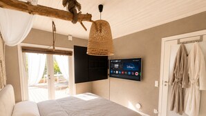 Un dormitori amb un llit, un televisor penjat i una porta amb abrics penjats.