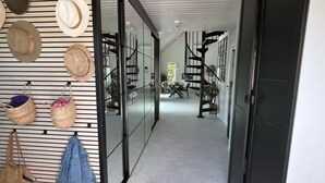 Un passadís de disseny modern, amb un penjador de barrets fixat a la paret i unes escales que condueixen a una altra habitació.