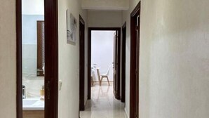 A hallway with a tiled floor and wooden doors, leading to a dining area with chairs and a table. - Z House Gueliz  Marrakech (Marrakech)