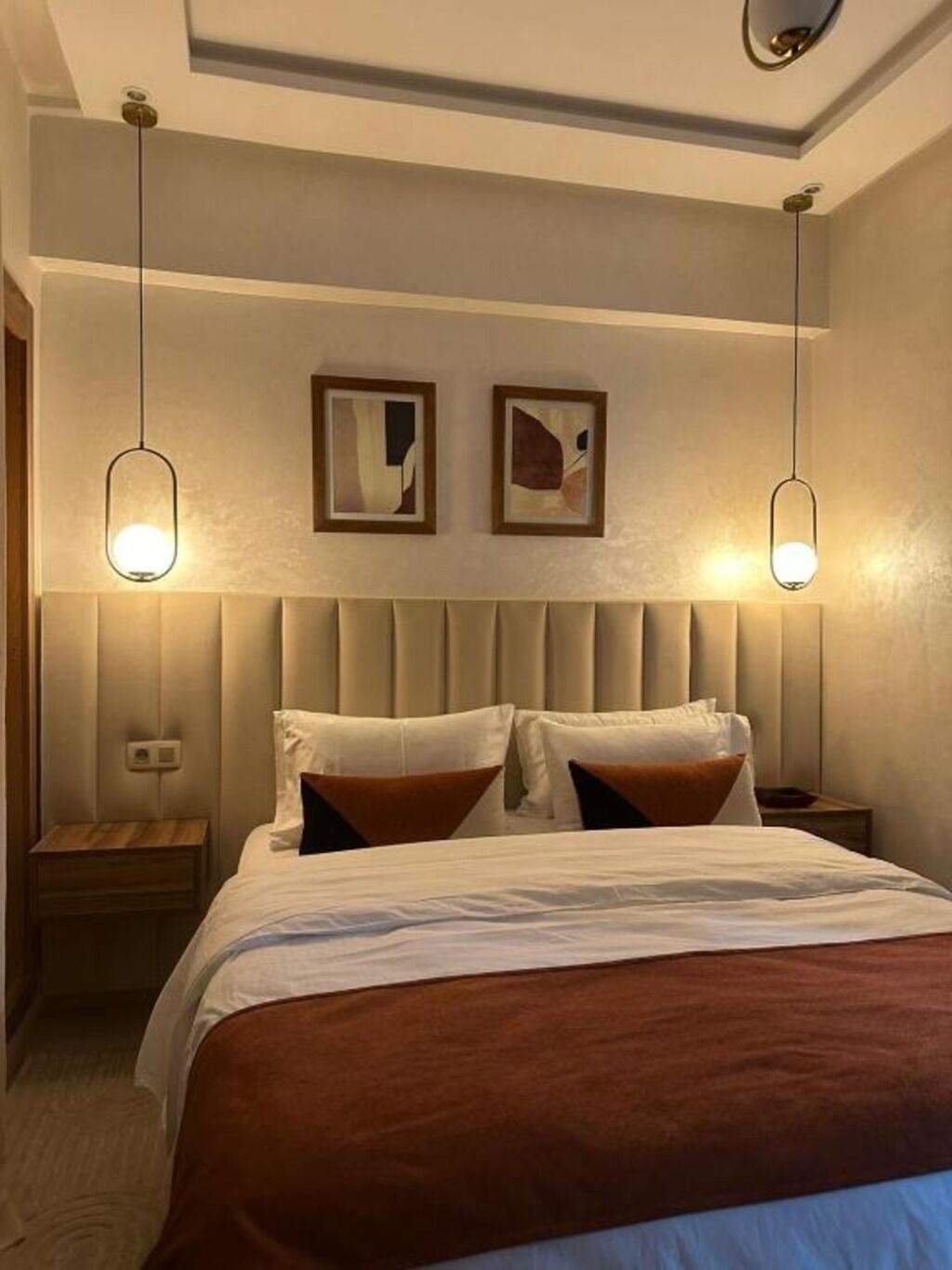 Et hotelværelse med en seng, to sengeborde og to hængende lamper.
