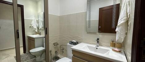 Une salle de bain moderne avec une douche à l’italienne en verre, un lavabo blanc et un meuble-lavabo en bois.