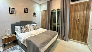 A modern bedroom with a large bed, a nightstand, a wardrobe, and a sliding glass door to a balcony. - Z House Gueliz  Marrakech (Marrakech)
