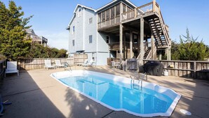A backyard with a swimming pool, a wooden deck, and a house with a balcony. - New Listing! Pool, Hot Tub & 2-Min Walk to Beach! (Corolla)