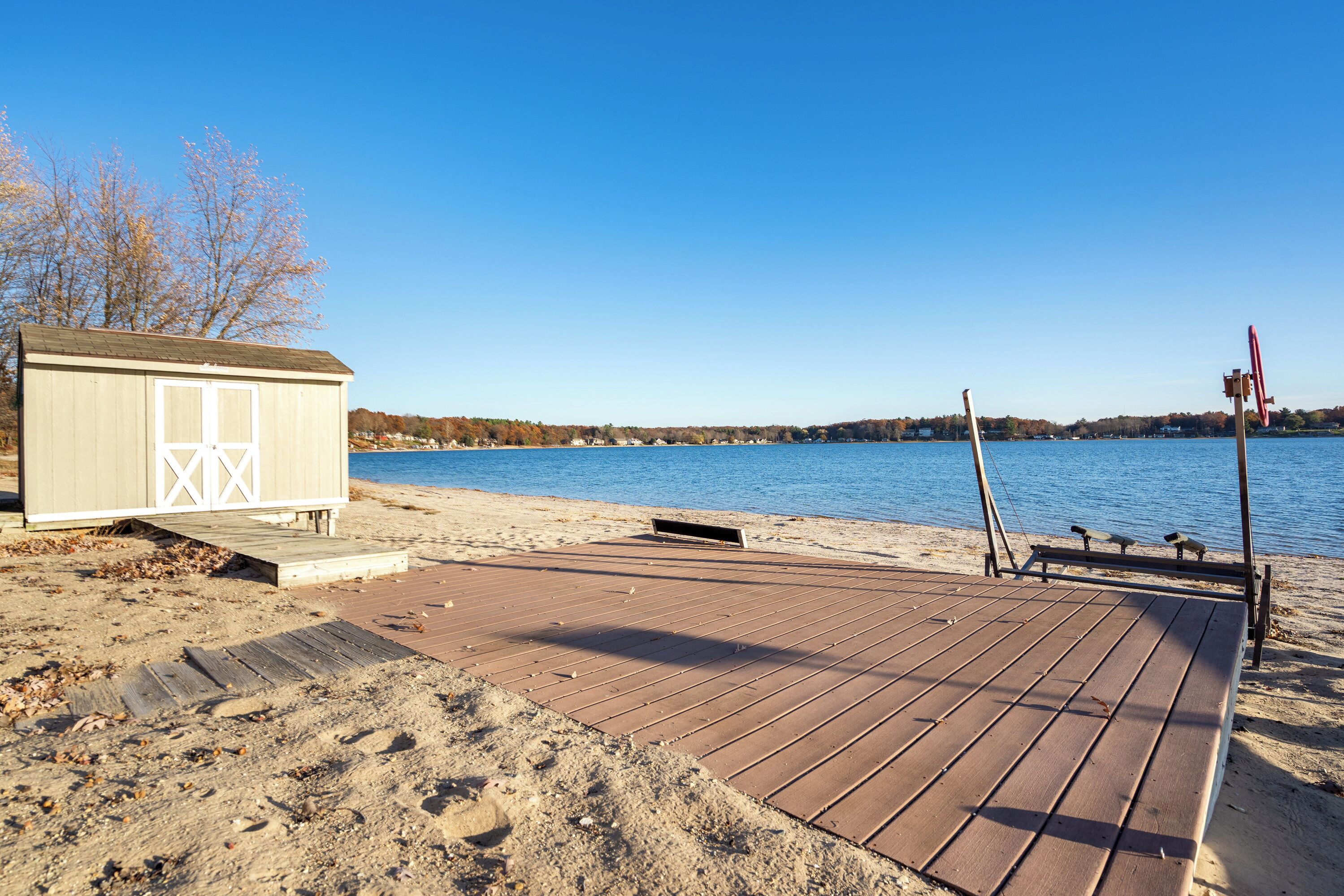 Une terrasse en bois qui mène à un petit abri situé au bord d’un lac.
